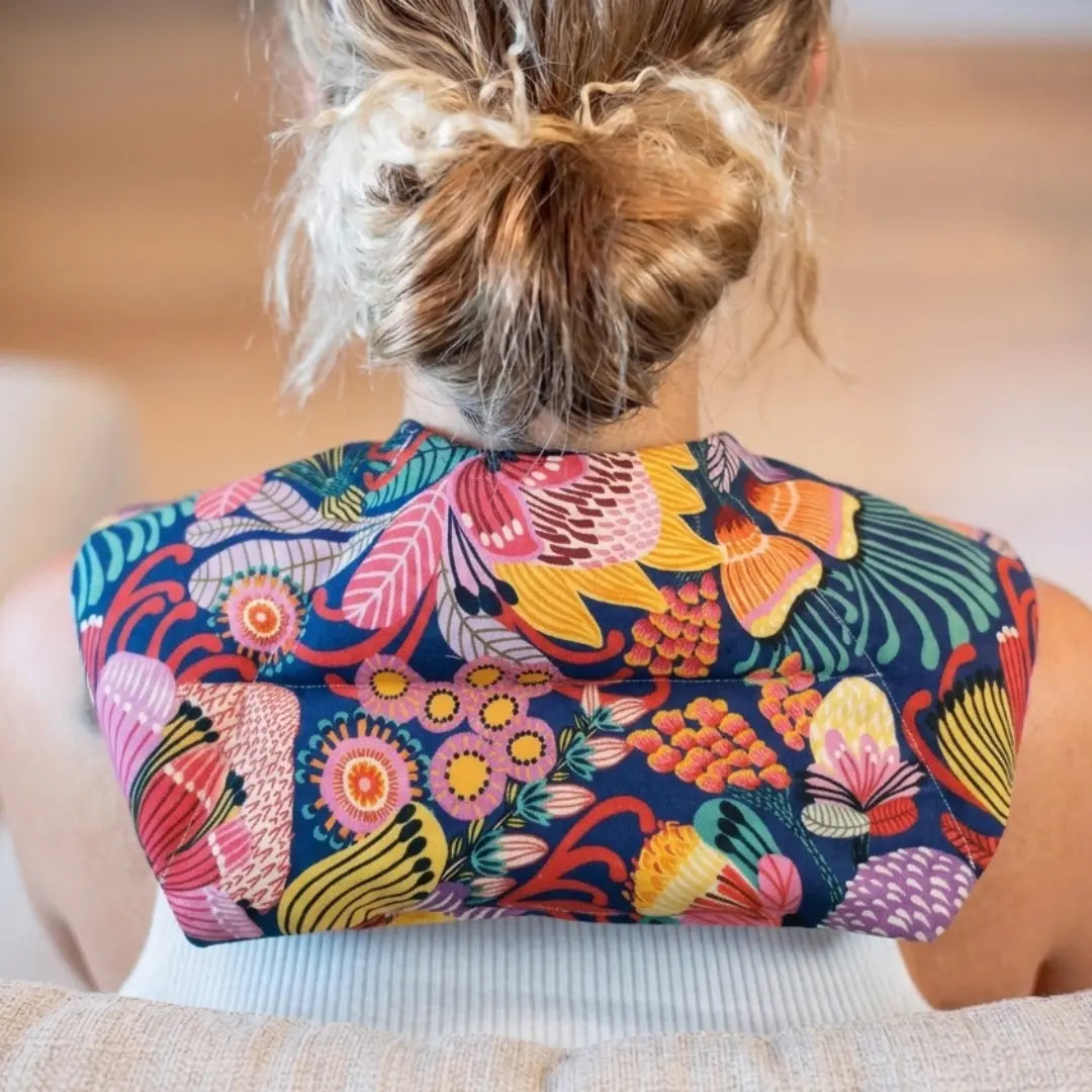 Colourful Australian floral neck heat pack filled with lupin seeds, worn across the shoulders for hot or cold therapy